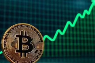 Bitcoin का डिजिटल चिह्न, बाजार ग्राफ़ के सामने चमकता हुआ।